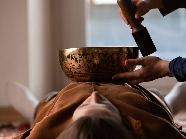 A Tibetan singing bowl being played over a resting client during a healing session