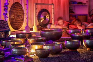 A candlelit room filled with Tibetan singing bowls and a gong during a group sound bath